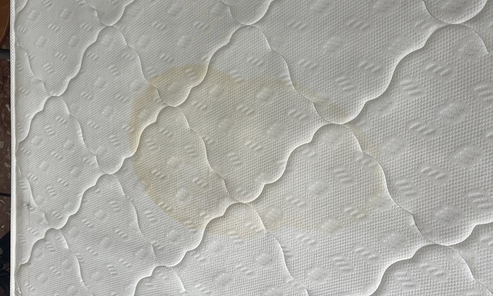 Macchia gialla ossidata sul materasso prima del trattamento