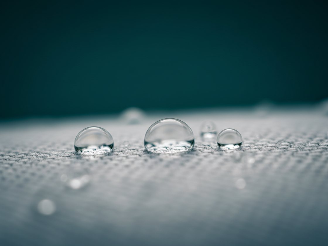 Gocce d’acqua che perlano sulla superficie di un tessuto intrecciato